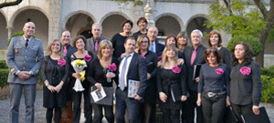 Grupo de pessoas em frente a um edifício histórico, vestidas maioritariamente de preto, posando para fotografia de grupo após um evento cultural.